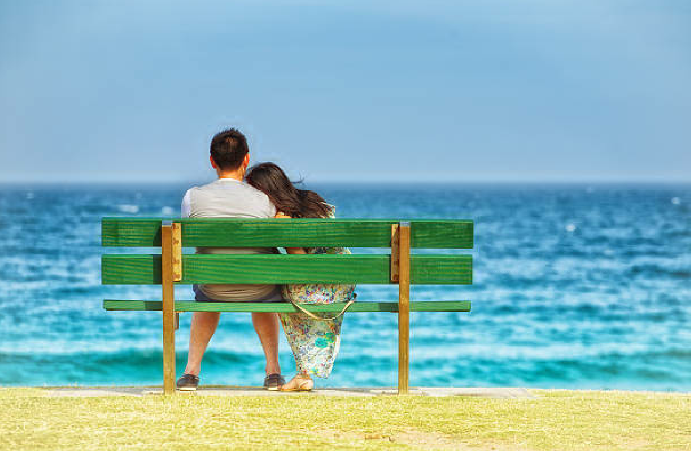 couple_sitting_on_a_bench_looking_out_to_sea